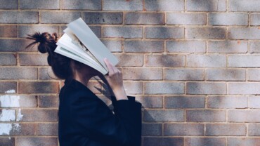 woman covering her face with white book